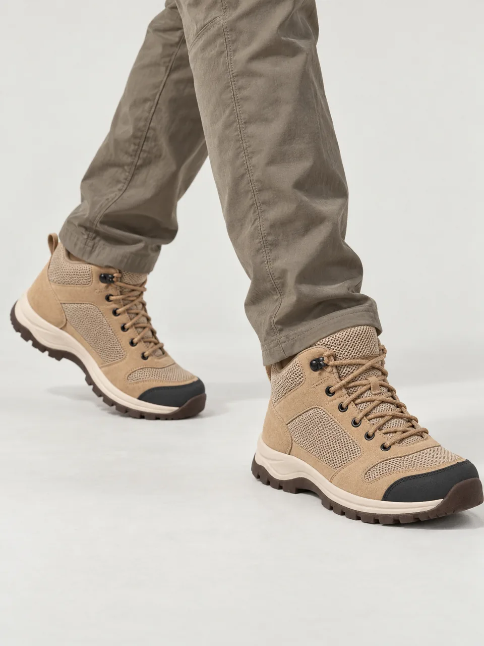 Man in his 20s, Black British, slim build, walking a sunny clifftop path in shorts, framed from the knee down wearing the Hale Men's Foss Vent Mid Walking Boot in Sandstone