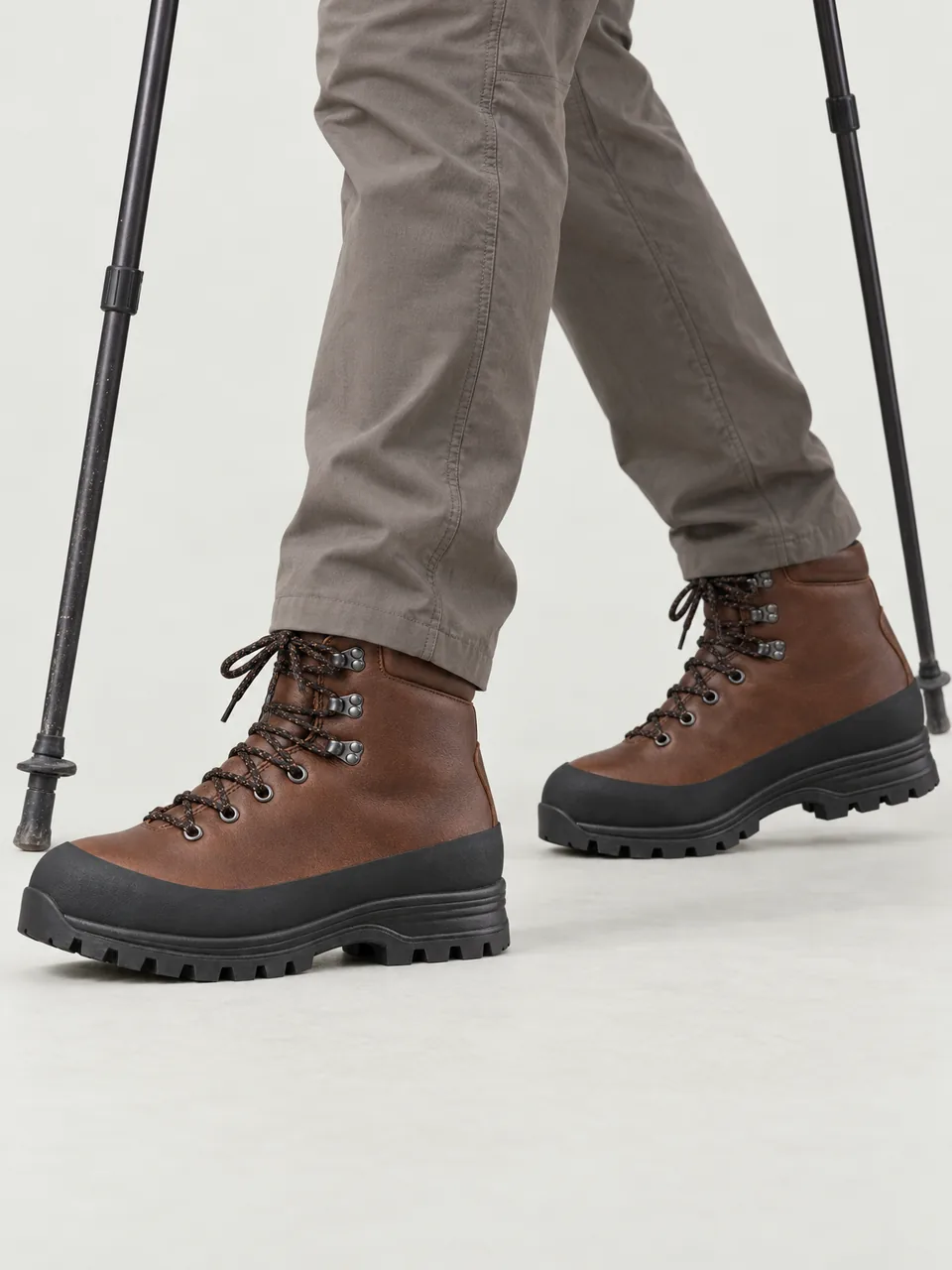 Man in his 60s, white, tall and wiry, walking a rocky Lakeland ridge with poles, framed from the knee down wearing the Wayfell Men's Garburn Leather Walking Boot in Brown