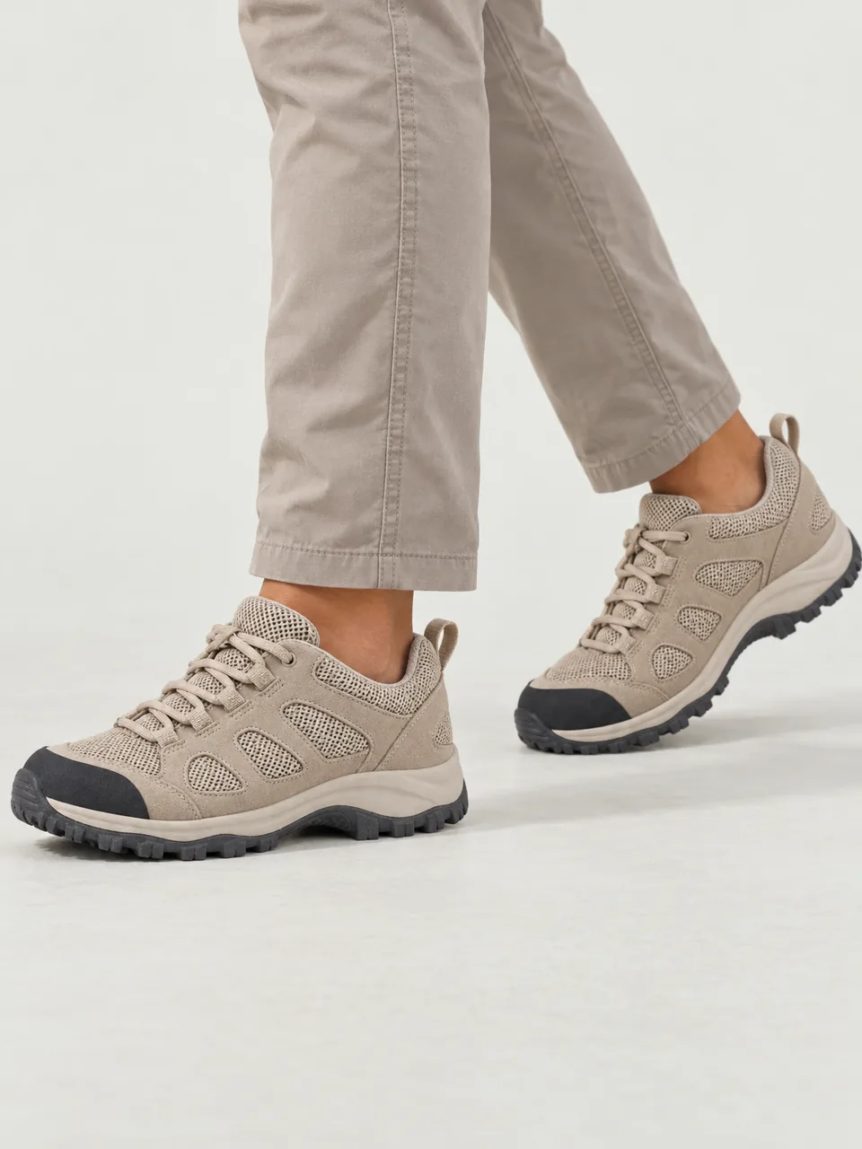Woman in her 20s, mixed heritage, curly hair, walking a dry fell path in shorts on a sunny day, framed from the knee down wearing the Wayfell Women's Sty Head Vent Walking Shoe in Stone