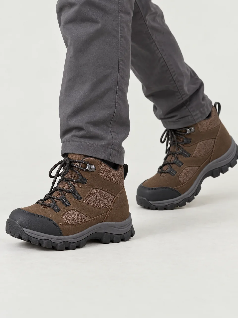 Boy about 9, East Asian, walking through wet grass on a hillside path, cropped to feet and lower legs wearing the Hale Kids' Ghyll Waterproof Walking Boots in Peat
