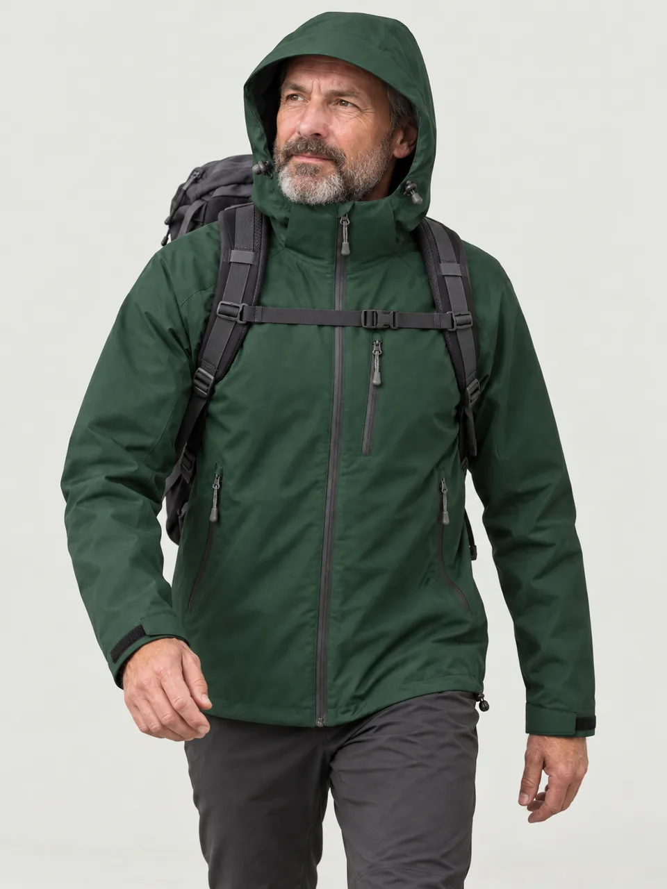 White man in his 50s, bearded, walking uphill with a 30-litre pack, hood up wearing the Hale Men's Cleugh 2.5L Waterproof Jacket in Holloway