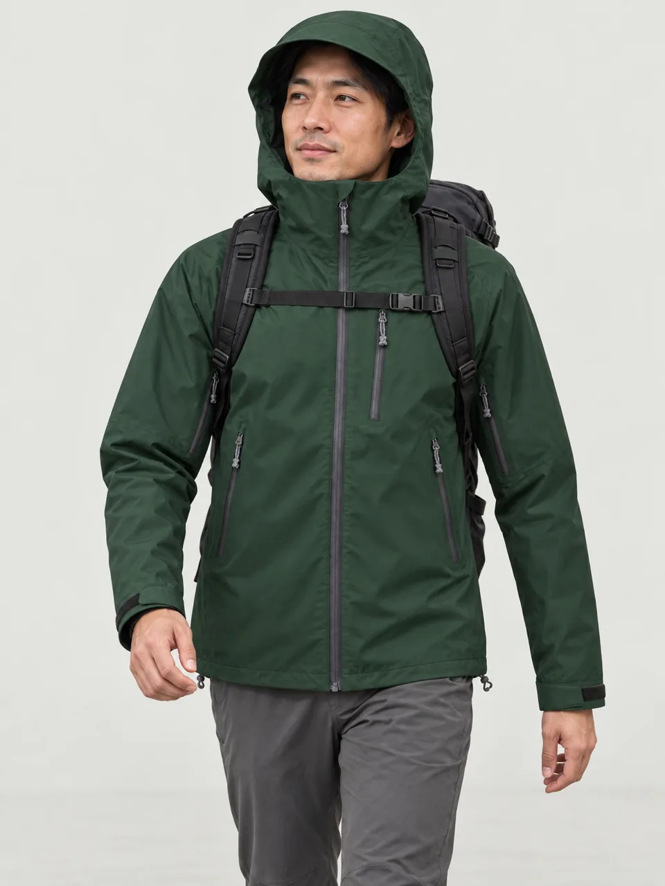 East Asian man in his 30s, slim build, walking a moorland path with a 30-litre pack, hood up wearing the Hale Men's Brackwater 3L Waterproof Jacket in Holloway