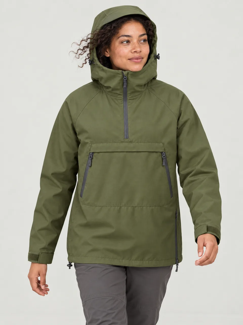 Mixed-race woman in her 20s, walking along a windy coastal headland, hood up wearing the Hale Mosser 2.5L Waterproof Smock in Moss
