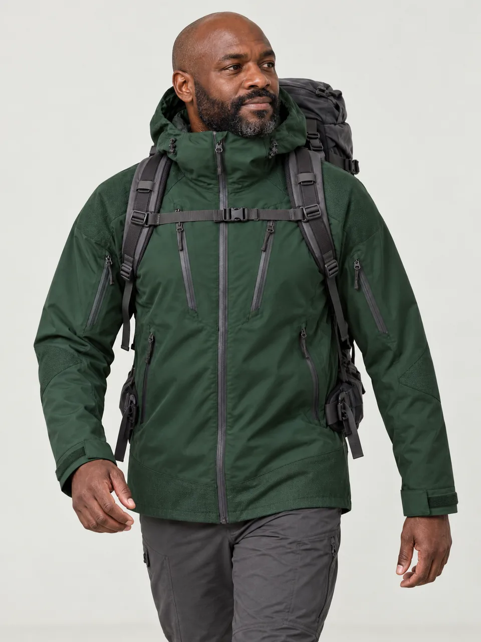 Black man in his 40s, broad build, walking a rough track with a large 60-litre pack wearing the Hale Men's Swale 3L Waterproof Jacket in Holloway