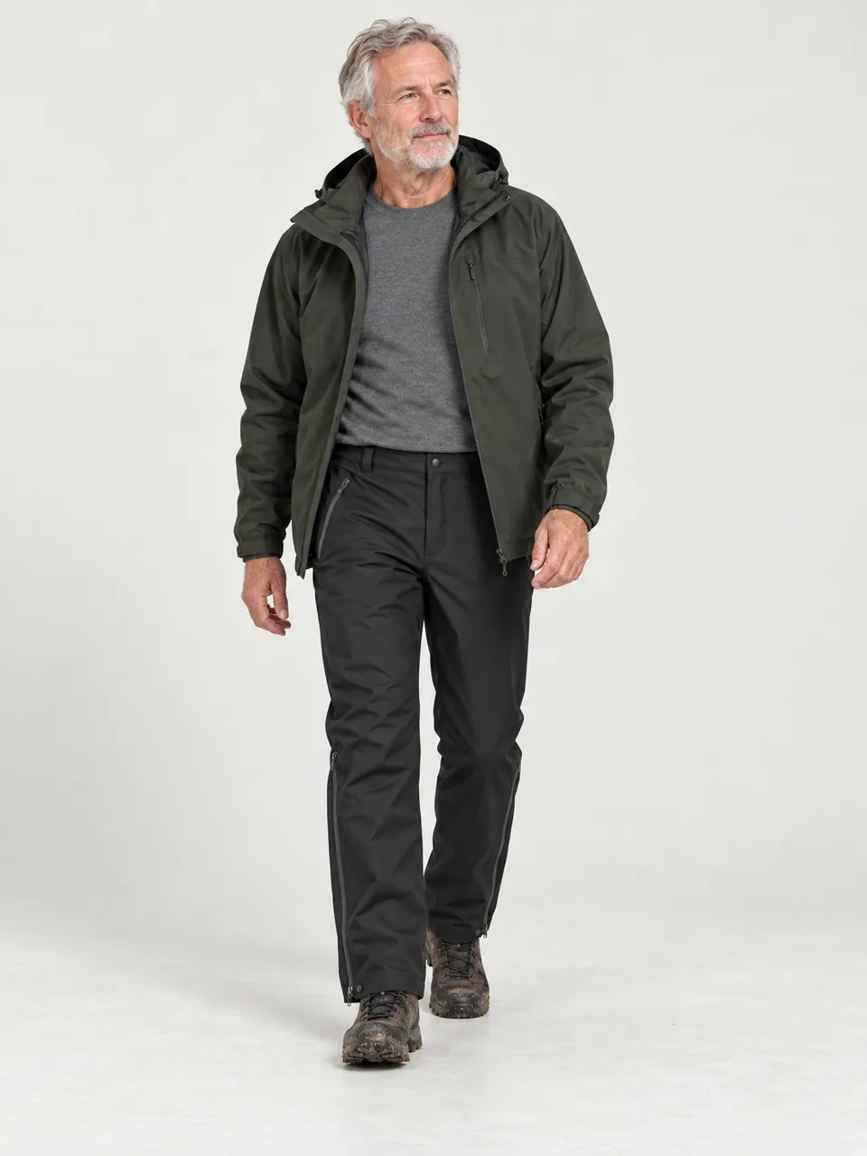 White man in his 60s, walking a muddy forest track in boots and a waterproof jacket wearing the Hale Men's Laithe 2L Waterproof Trousers in Soot