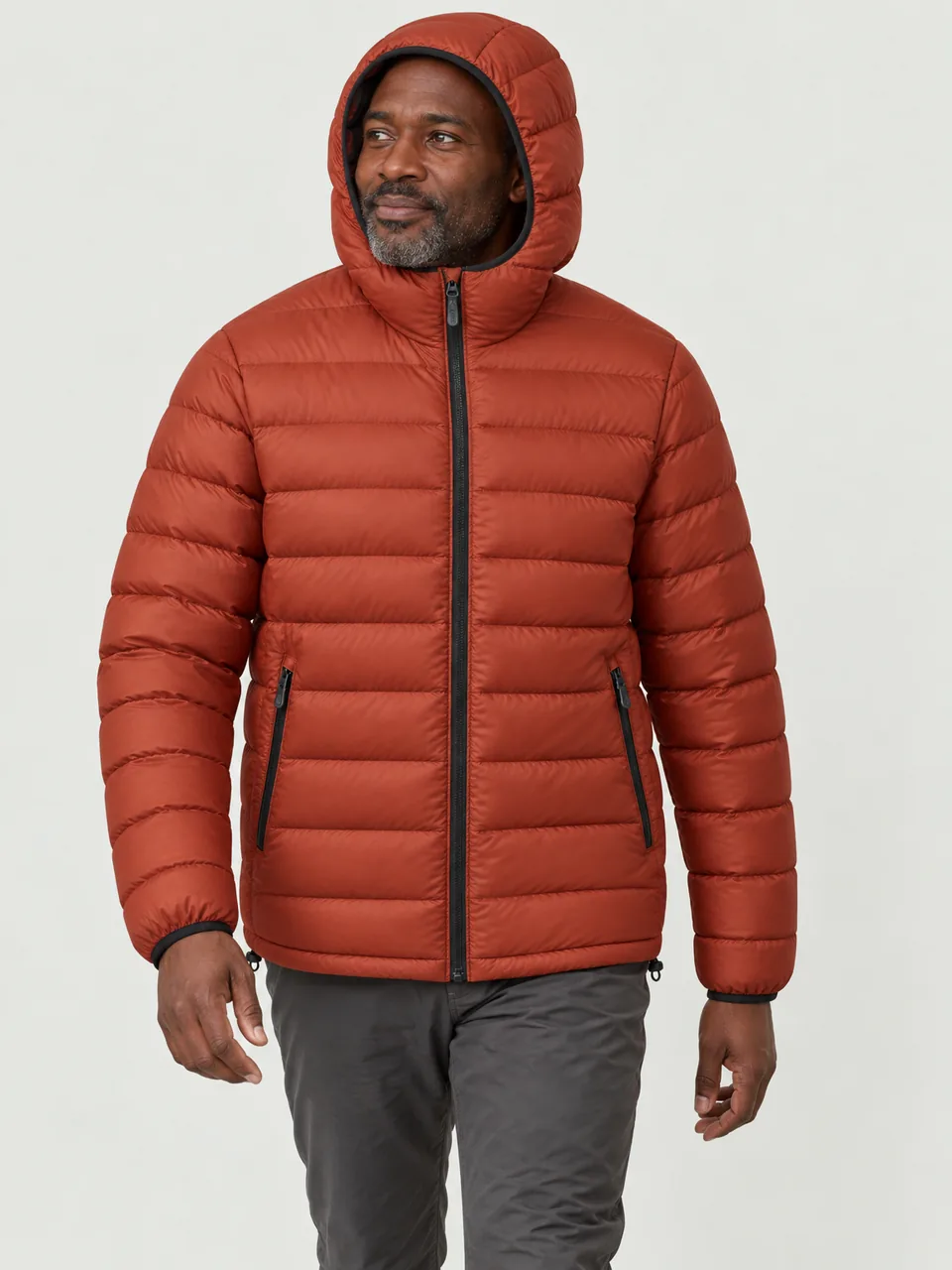 Black man in his 40s, walking round a lochside wild camp at dusk, hood up wearing the Swift Men's Goldcrest 120 Down Jacket in Ember
