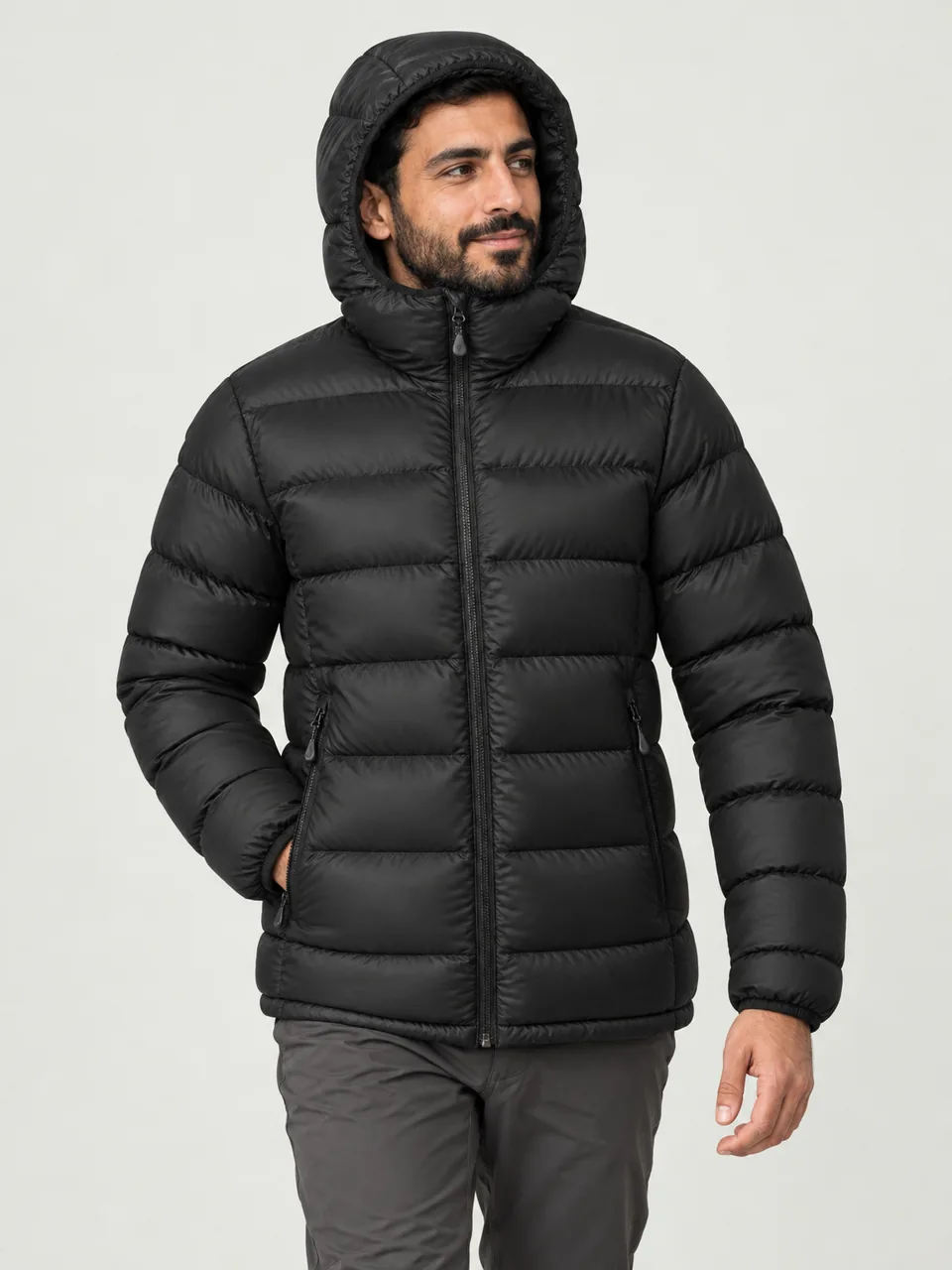 Arab man in his 30s, walking across a snowy plateau at dusk, hood up wearing the Northwold Men's Rime 800 Hooded Down Jacket in Black