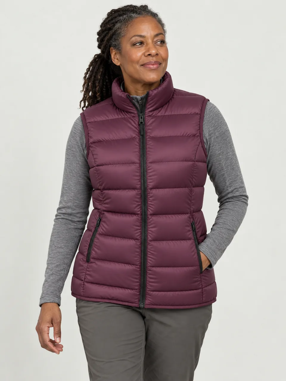 Black woman in her 40s, walking a lakeside path on a cold morning, gilet over a base layer wearing the Northwold Women's Rime 800 Down Gilet in Plum