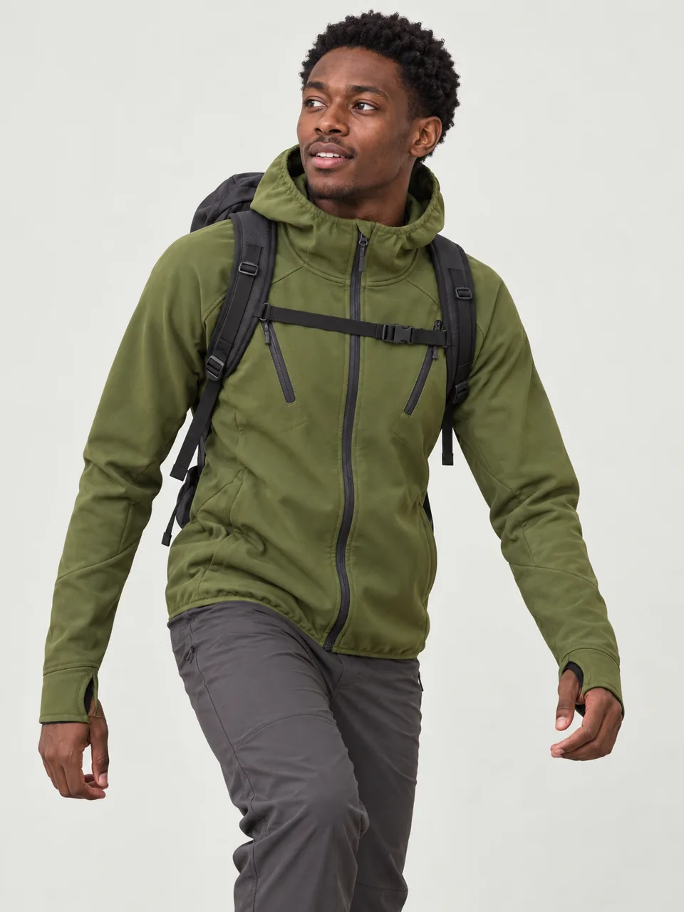 Black man in his 20s, slim, scrambling up a rocky ridge with a small pack wearing the Swift Men's Redstart 340 Softshell Hoody in Moss