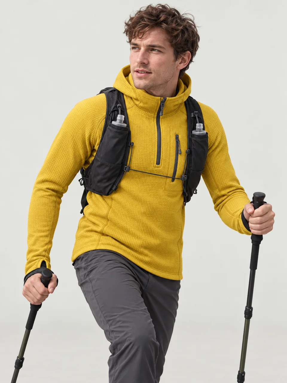 Lean man in his 20s moving fast up a rocky ridge with poles and a small running vest wearing the Swift Men's Dipper 265 Grid Hoody in Gorse