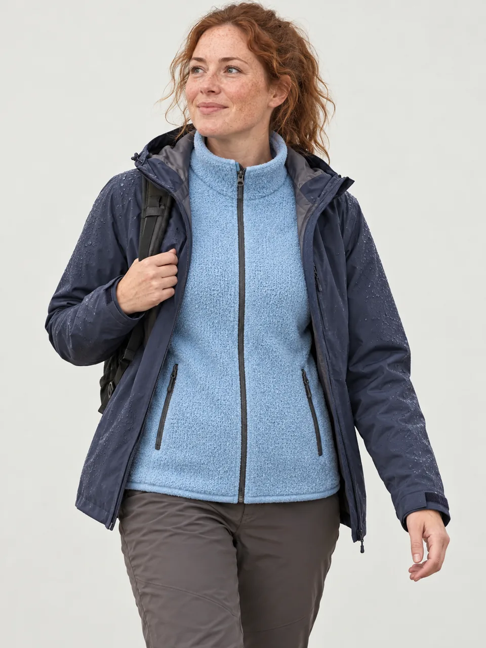 Freckled Irish woman in her 30s walking a stony track in light rain, an open shell over the fleece wearing the Swift Women's Whimbrel 190 Air Fleece in Sky