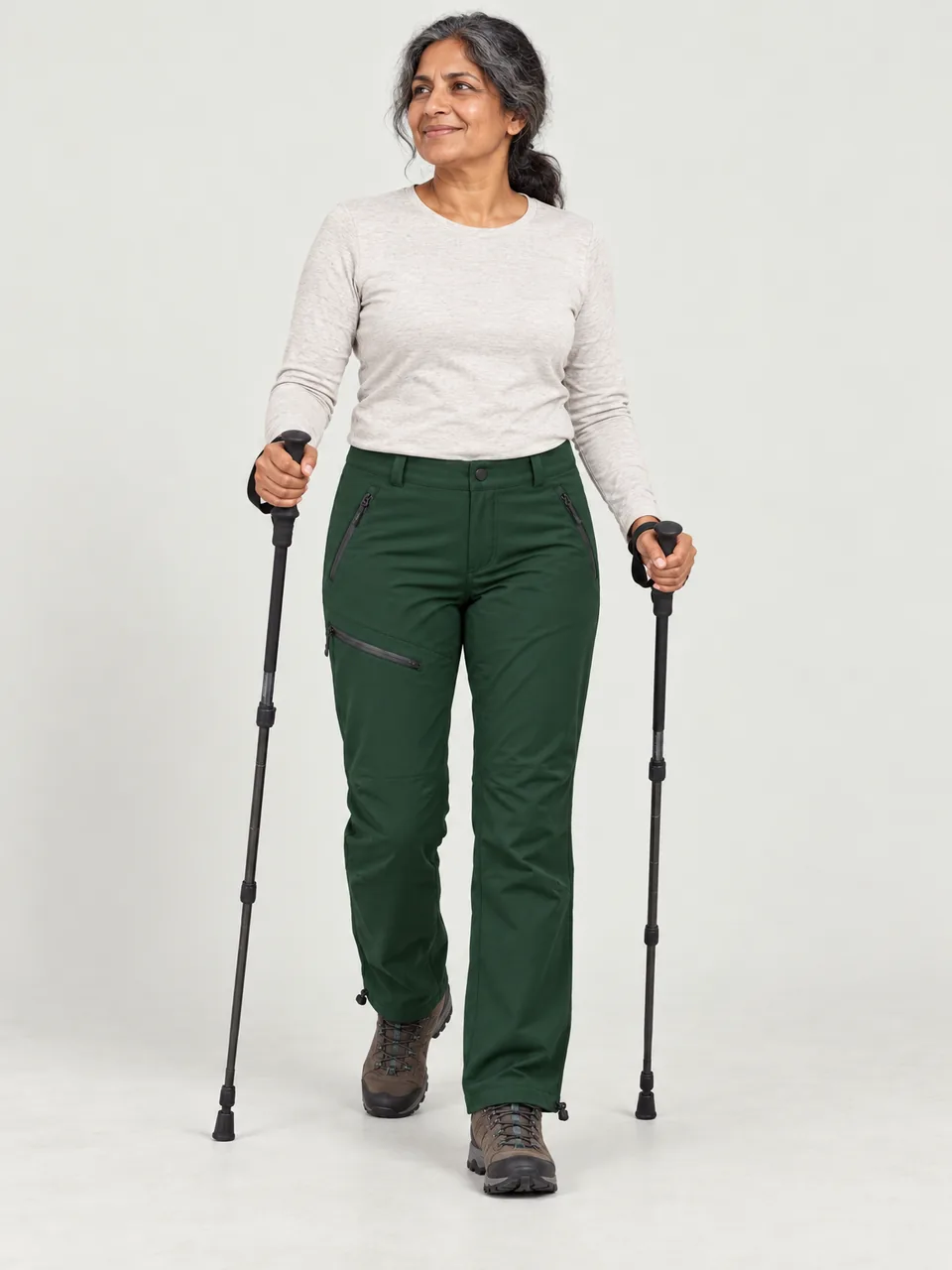 South Asian woman in her 50s walking along a limestone dale path with poles wearing the Hale Women's Inbye Walking Trousers in Holloway