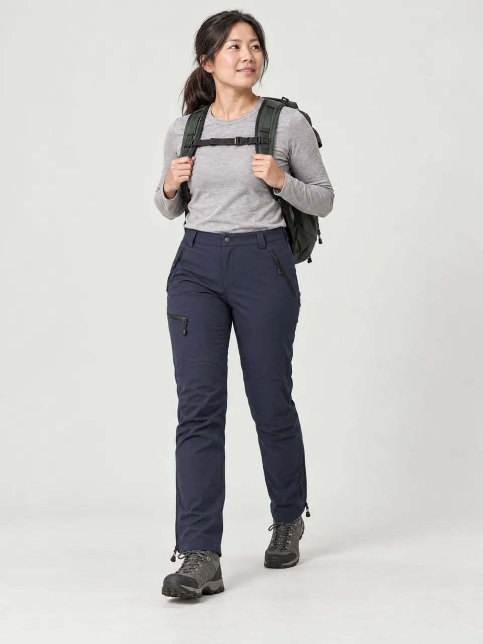 East Asian woman in her 30s mid-scramble on a rocky arete with a light pack wearing the Rakefoot Women's Trod Stretch Trousers in Dark Navy