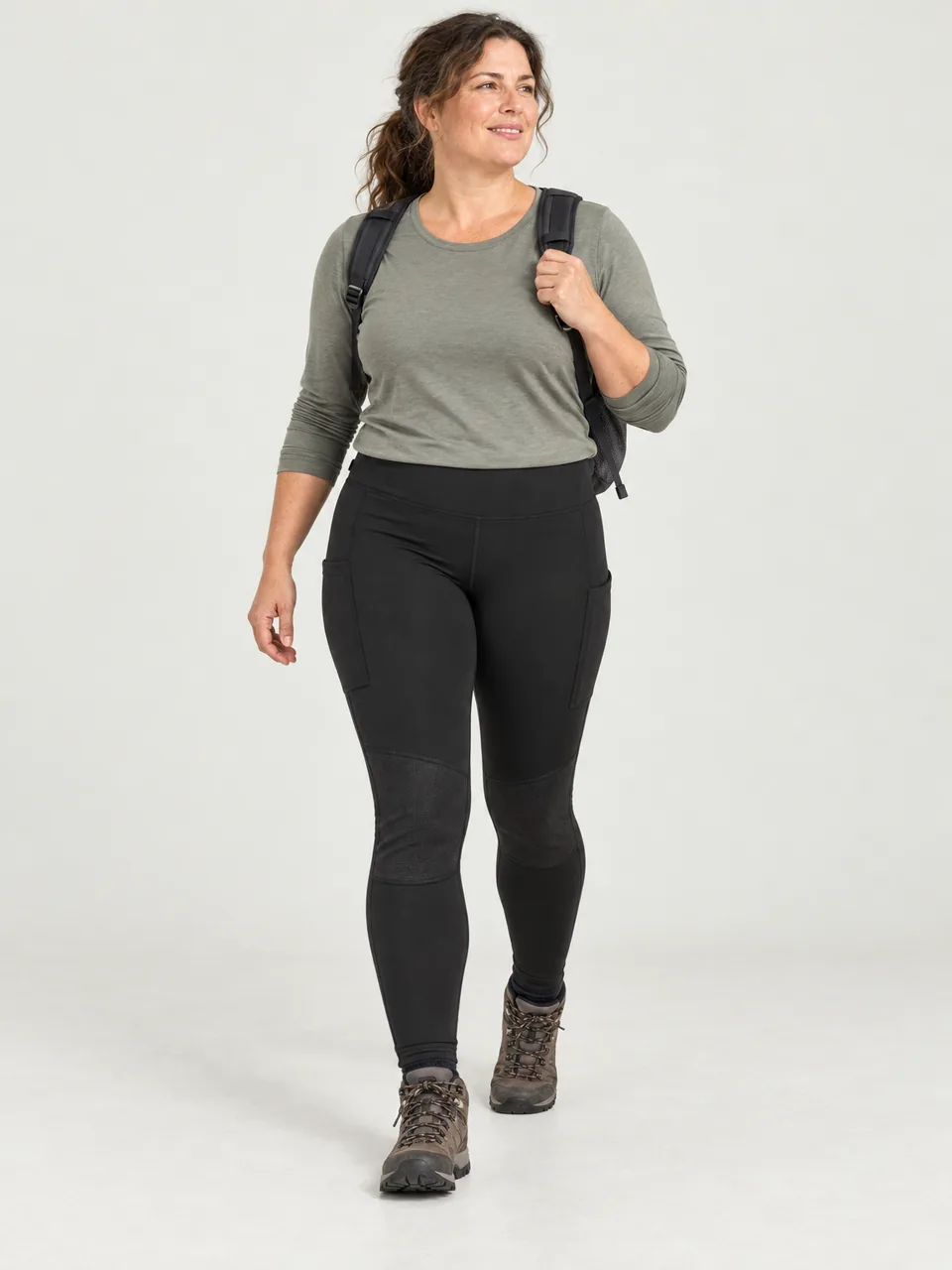 Curvy woman in her 40s walking up a cobbled lane towards open moor with a small daypack wearing the Rakefoot Women's Ginnel Walking Leggings in Black